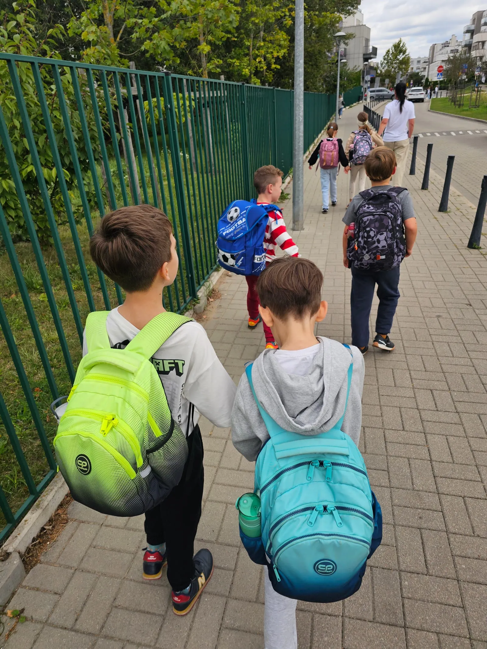 Children with backpacks walking to their lesson, seen from behind